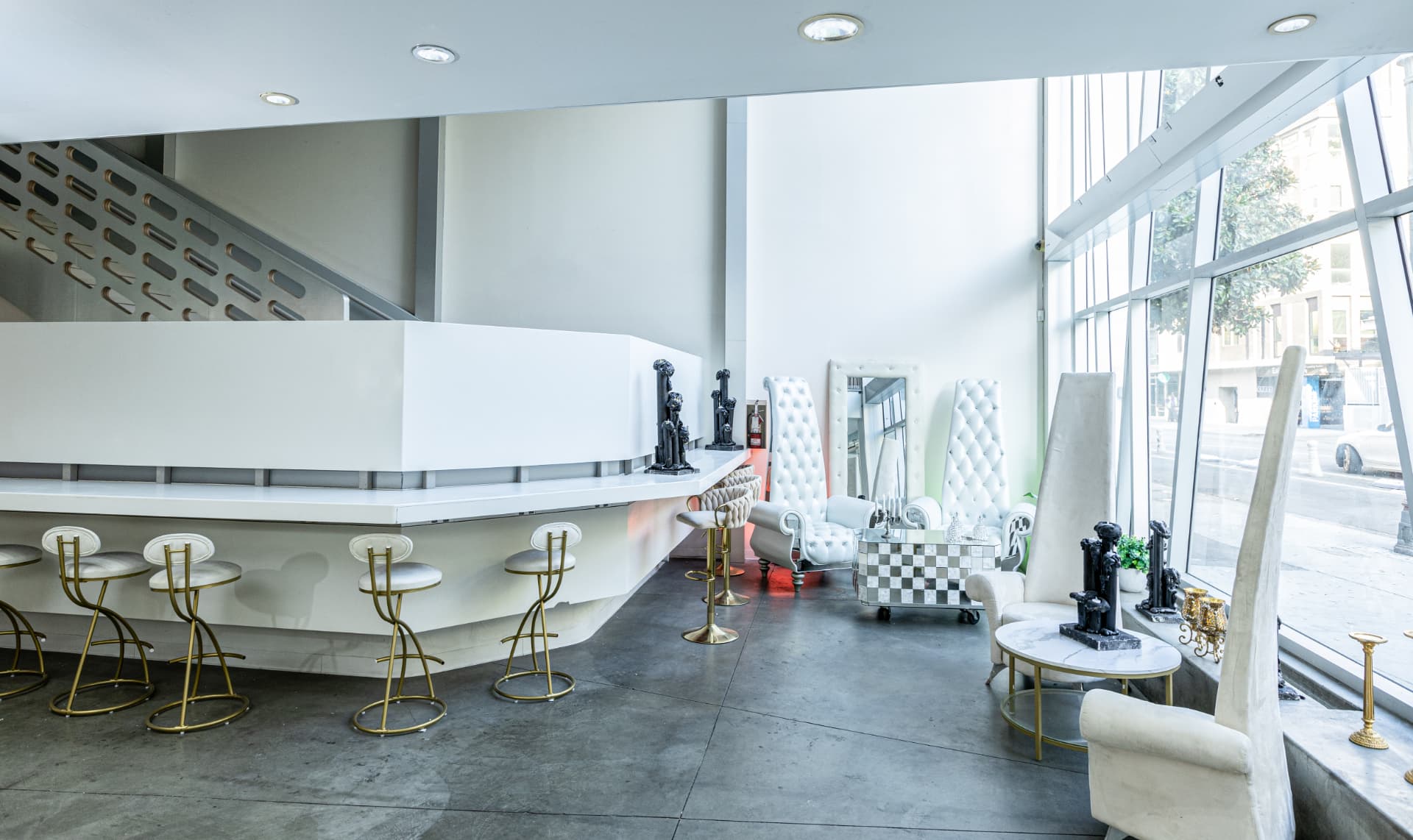 The sculptural white lobby bar with brass stools beneath the atrium glass