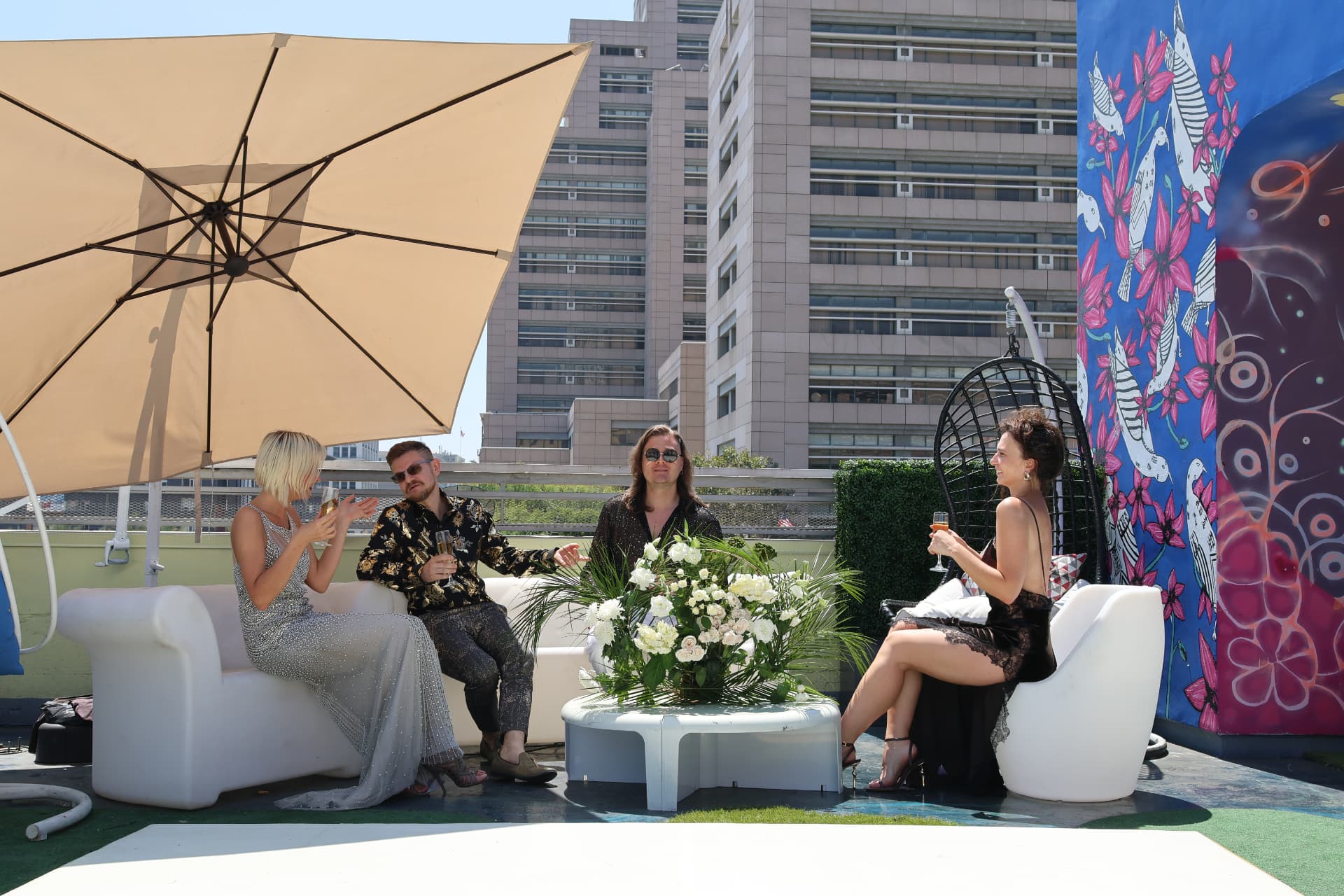 Guests with champagne in the rooftop lounge beneath a shade umbrella