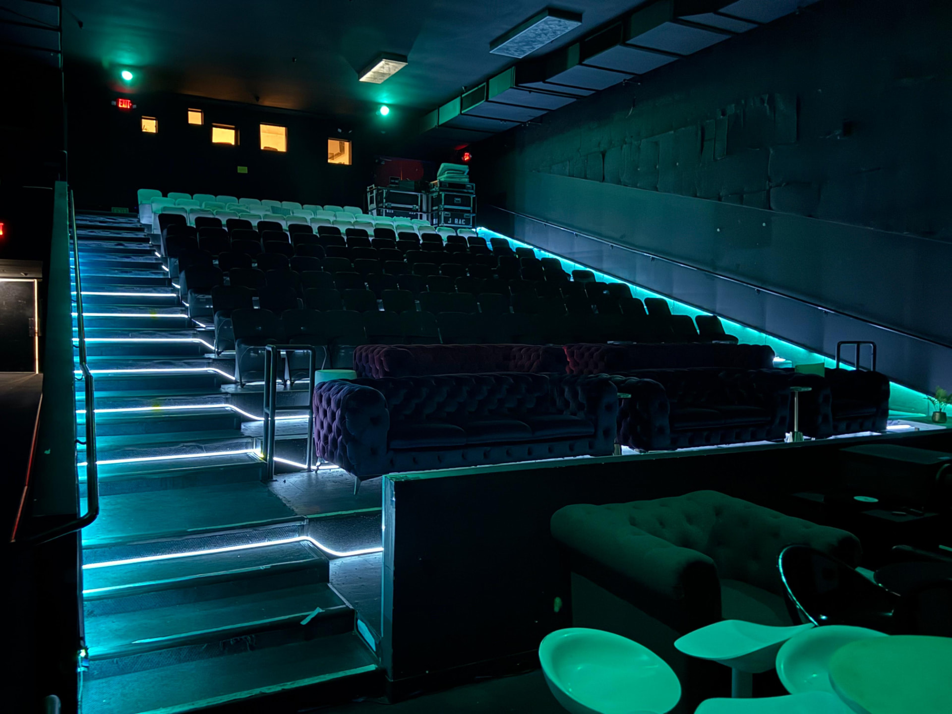 Theater seating and velvet sofas washed in teal light