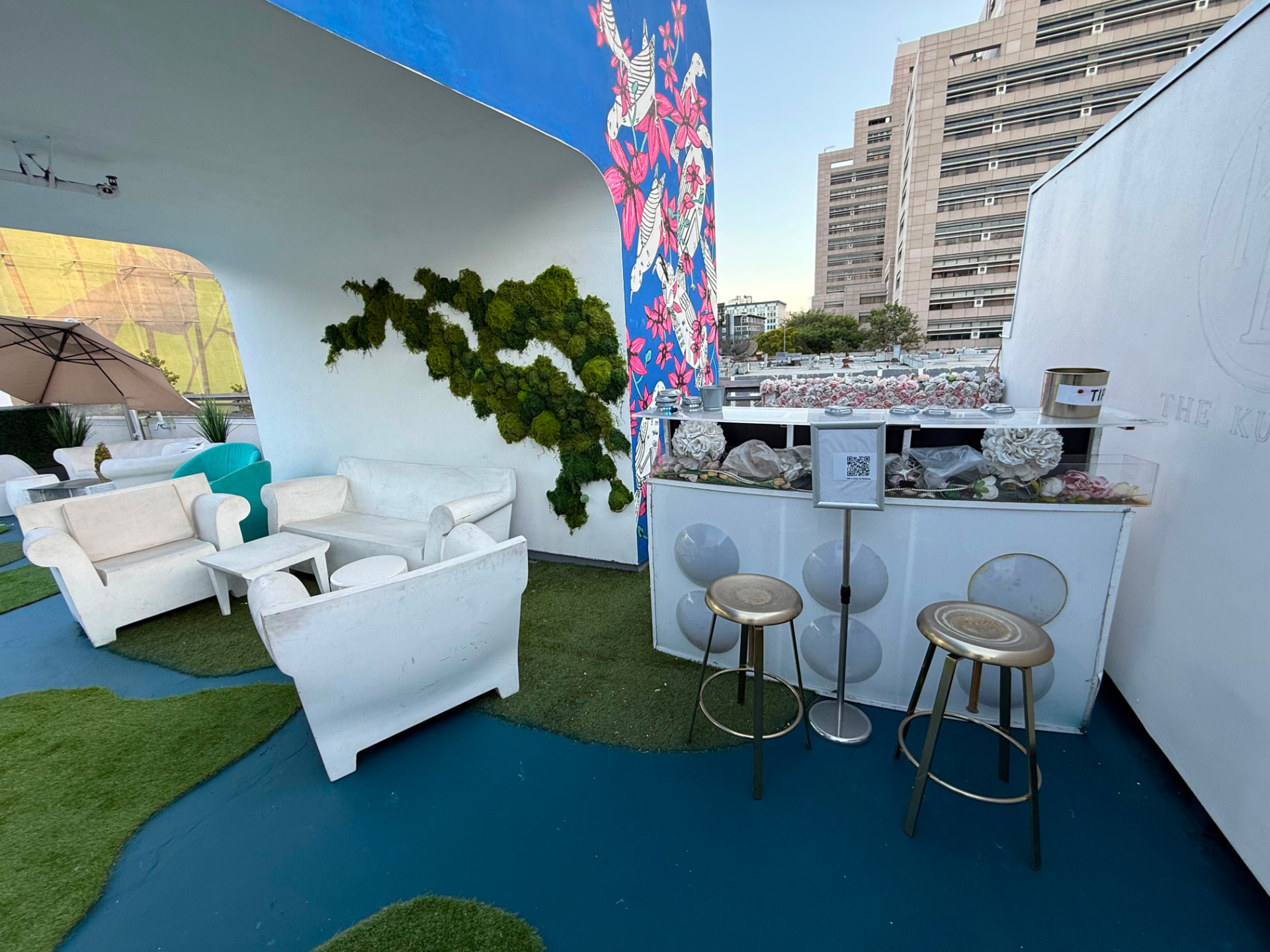 The rooftop bar with brass stools, moss art and the floral mural