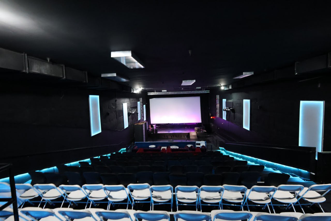 The empty theater house with blue acoustic panels and the projection screen