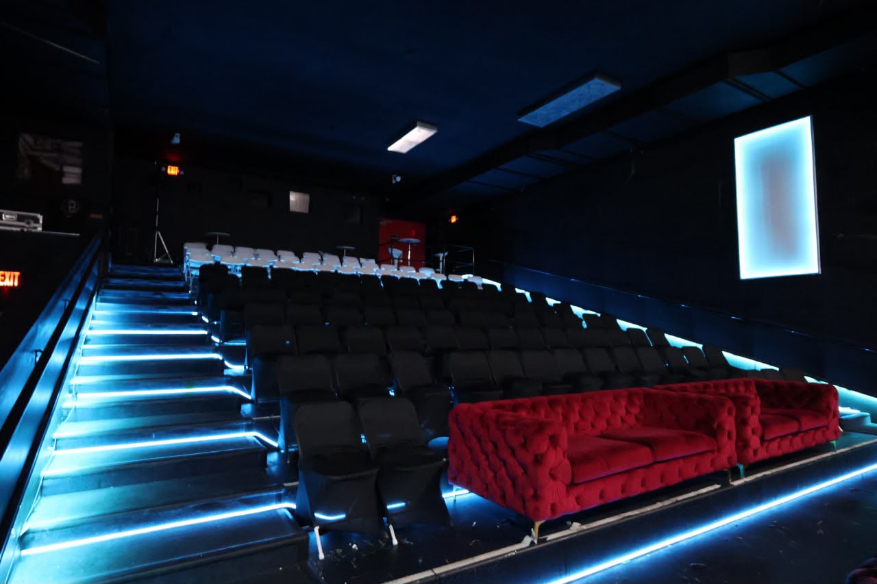 A red velvet sofa on the tiered theater risers under blue light