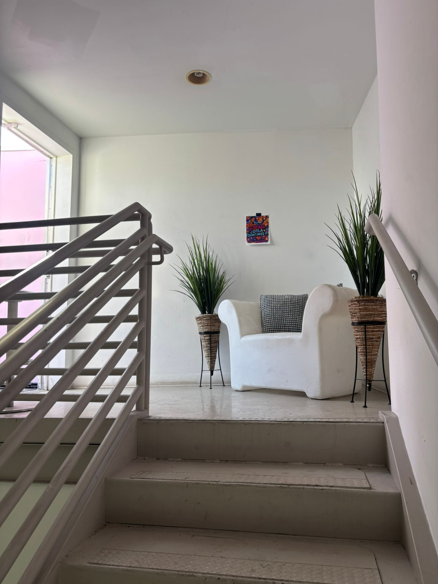 A sculptural white armchair on the stair landing with tall grasses