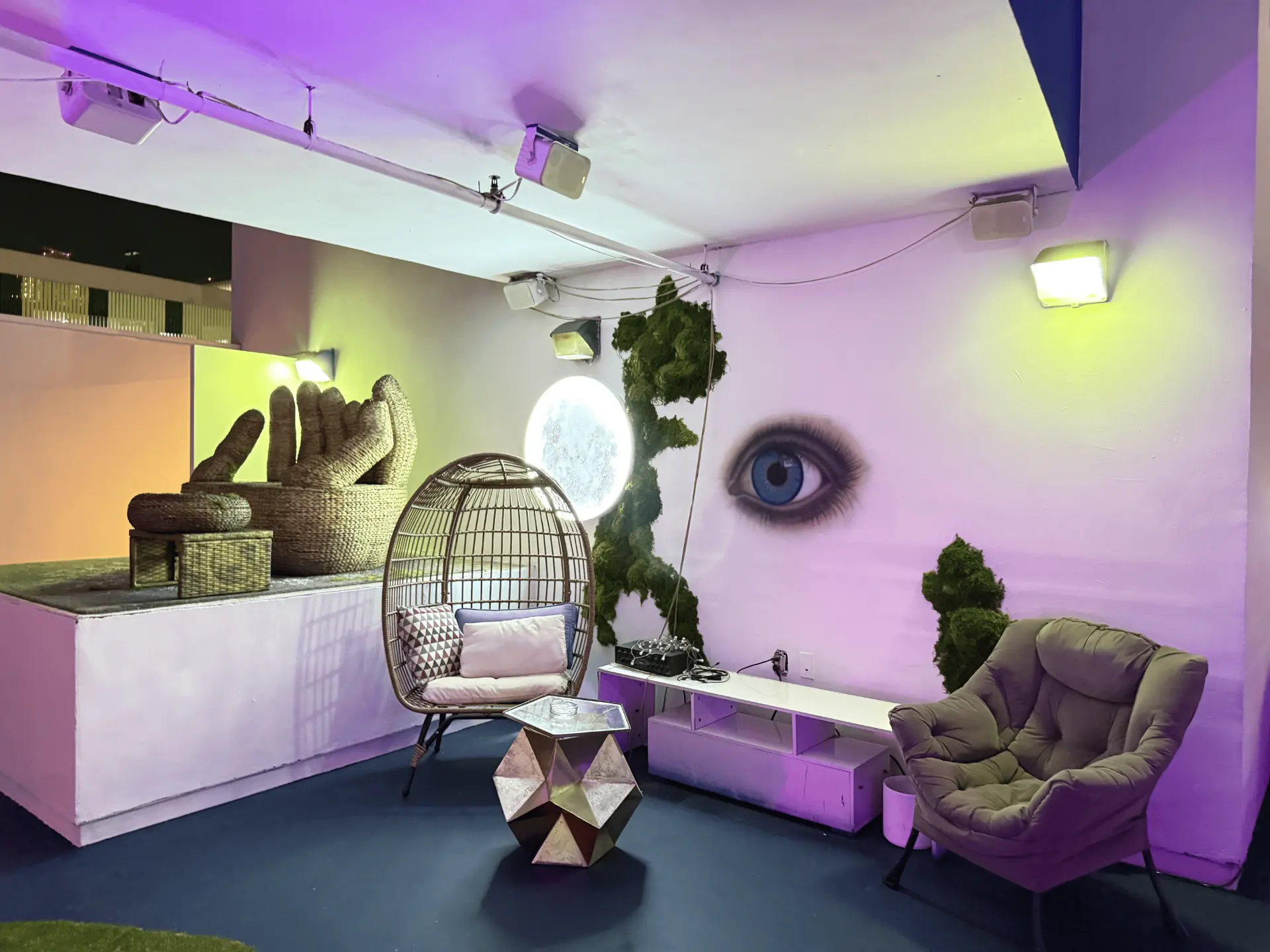 The rooftop lounge at night under purple light with the eye mural